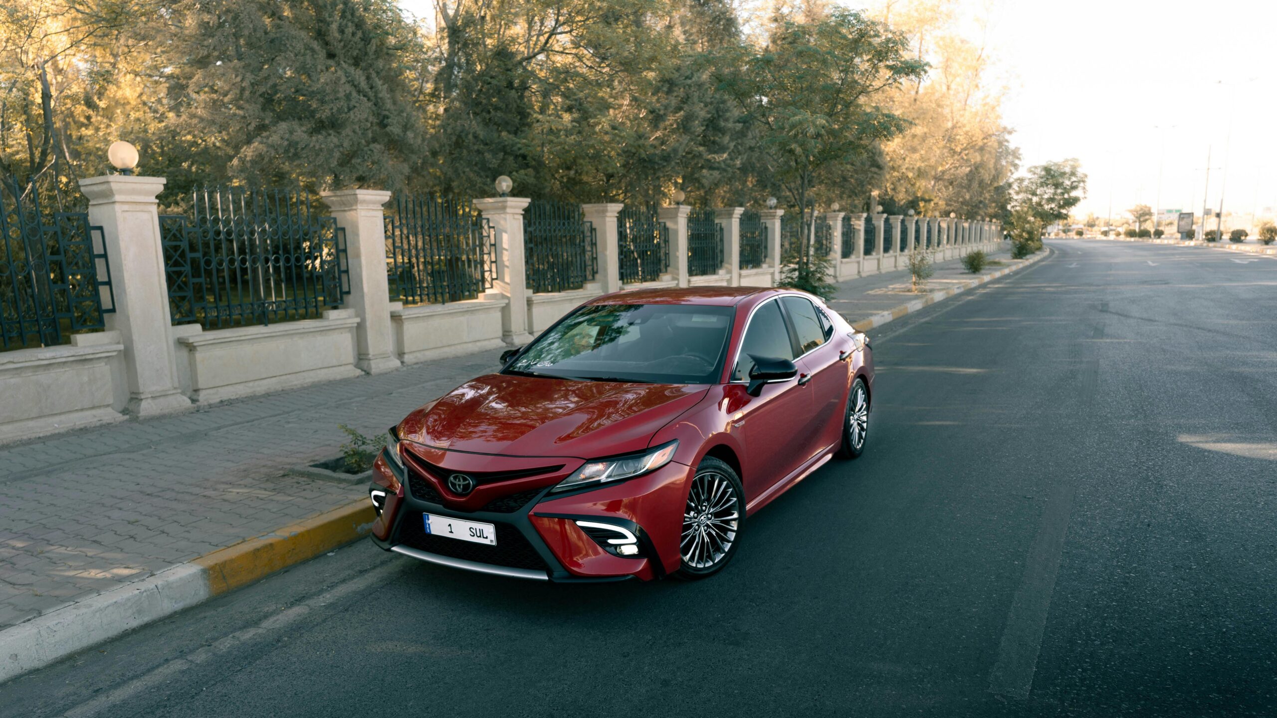 Red Toyota sedan parked near a stylish urban street, showcasing sleek design and elegance.